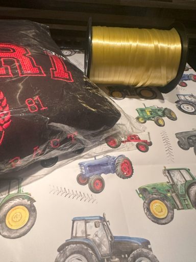 Tractor Wrapping Paper White Paper with different coloured tractors on with gold ribbon ready to be used.